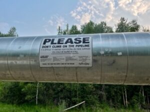 Sign on Alaska Pipeline that reads Please Do Not Climb on Pipeline