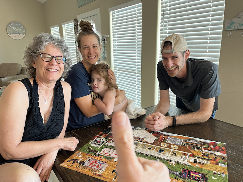 Family surrounding table with completed jigsaw puzzle