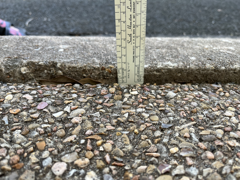 Curb with ruler showing sidewalk subsidence 